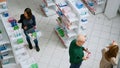 Diverse clients waiting in line to pay for medication at pharmacy shop counter