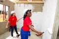 Diverse Community members join PWC`s staff in building a low cost house in Soweto