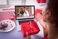 Diverse couple making valentines date video call both holding gifts and blowing kisses Royalty Free Stock Photo