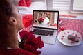 Diverse couple making valentines date video call on laptop both holding flowers and blowing kisses Royalty Free Stock Photo