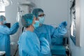 Diverse couple of male and female surgeons in operating theatre wearing face masks looking at screen