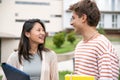 Diverse couple smiling and holding folders in a campus.Two young students looking each other smiling and satisfied in