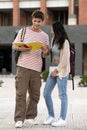 Diverse couple standing and reading notes in a campus. Two young students looking notebook smiling and studying in the Royalty Free Stock Photo