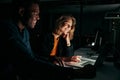 Diverse creative business people working with laptop overtime at night in low light at office Royalty Free Stock Photo