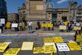 Diverse crowd of people gathered in a city setting, each holding various signs and placards