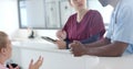 Diverse doctors talking to medical recepcionist sitting at front desk at hospital, slow motion