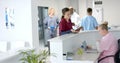 Diverse doctors talking to medical recepcionist sitting at front desk at hospital, slow motion