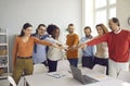 Happy diverse team of enthusiastic business people joining hands in group office meeting