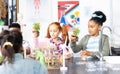 Diverse elementary schoolchildren holding plants in school ecology class