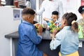 Diverse elementary schoolchildren studying plants with male teacher in school class