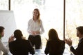 Diverse employees applaud greeting female speaker at meeting