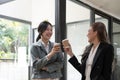 Diverse employees chatting during coffee break, walking in modern office, Asian businesswoman wearing glasses sharing Royalty Free Stock Photo