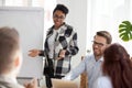 Diverse employees laugh during flipchart presentation at meeting Royalty Free Stock Photo