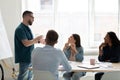 Diverse employees listening to confident coach mentor at meeting
