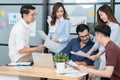 Diverse employees in office brainstorming while discussing ideas for new project, using laptop. Multiracial coworkers gather in Royalty Free Stock Photo