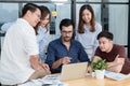 Diverse employees in office brainstorming while discussing ideas for new project, using laptop. Multiracial coworkers gather in Royalty Free Stock Photo