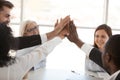 Diverse employees team giving high five at meeting close up