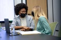 Diverse female business colleagues wearing masks laughing in meeting room Royalty Free Stock Photo