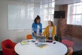 Diverse female colleagues standing at meeting room discussing looking at laptop Royalty Free Stock Photo