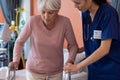 Diverse female doctor helping senior female patient use walking frame, copy space Royalty Free Stock Photo