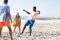 Diverse friends enjoy a casual game of soccer on the beach Royalty Free Stock Photo