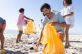 Diverse friends, a group of people, clean a beach by collecting trash Royalty Free Stock Photo