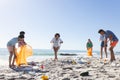 Diverse friends, part of a group, clean up a littered beach, collecting trash Royalty Free Stock Photo