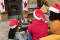 Diverse friends with santa hats having christmas video call with happy caucasian family Royalty Free Stock Photo