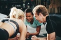 Diverse friends smiling while planking together during a gym wor