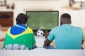 Diverse friends watching tv with football match on screen