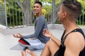Diverse gay male couple practicing yoga meditating and smiling on balcony Royalty Free Stock Photo