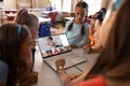 Diverse girls looking at teacher and students on laptop screen while studying online in classroom Royalty Free Stock Photo