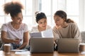 Diverse girls studying together at home, reading notes, using laptops Royalty Free Stock Photo