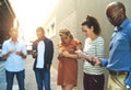 Diverse group of adult people connecting and social networking outside. Businesspeople texting, browsing and sharing