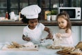 Diverse group of African American and Caucasian girls prepare the dough and bake cookies in the kitchen