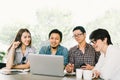 Diverse group of Asian business coworkers or college students using laptop in team casual meeting, startup project discussion Royalty Free Stock Photo