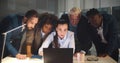 Diverse group of business people in office at night looking at laptop screen Royalty Free Stock Photo