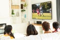 Diverse group of children siting on the couch and watching football match