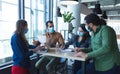 Diverse group of creative colleagues wearing face masks talking at meeting Royalty Free Stock Photo