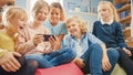 Diverse Group of Cute Small Children Sitting together on the Bean Bags Use Smartphone and Talk, Ha Royalty Free Stock Photo