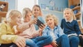 Diverse Group of Cute Small Children Sitting together on the Bean Bags Use Smartphone and Talk, Ha Royalty Free Stock Photo