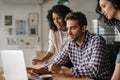 Three diverse designers using a laptop together at work Royalty Free Stock Photo