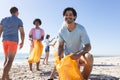 Diverse group of friends cleaning the beach and collecting trash Royalty Free Stock Photo