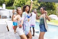 Diverse group of friends enjoying a pool party, dancing with drinks in hand Royalty Free Stock Photo