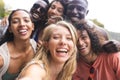 Diverse group of friends taking selfie, huddled close with wide smiles