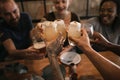 Friends sitting in a bar at night toasting with drinks Royalty Free Stock Photo