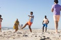 A diverse group of friends, young adults, enjoy a casual game of soccer on the beach Royalty Free Stock Photo