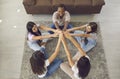 Diverse group of happy young women sitting in circle on floor, holding hands and smiling Royalty Free Stock Photo