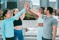 Diverse group of happy sporty people joining hands to high five for celebration of unity and support. Motivated athletes Royalty Free Stock Photo