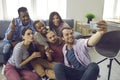 Diverse group of happy young friends taking funny selfie on mobile phone at home Royalty Free Stock Photo